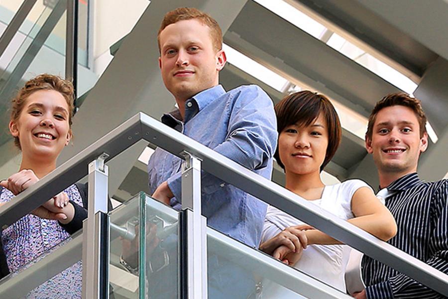 Image: 4 graduate students posing on balcony.