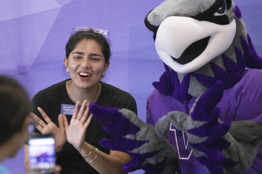 Willie Warhawk poses with another person in front of a purple backdrop.